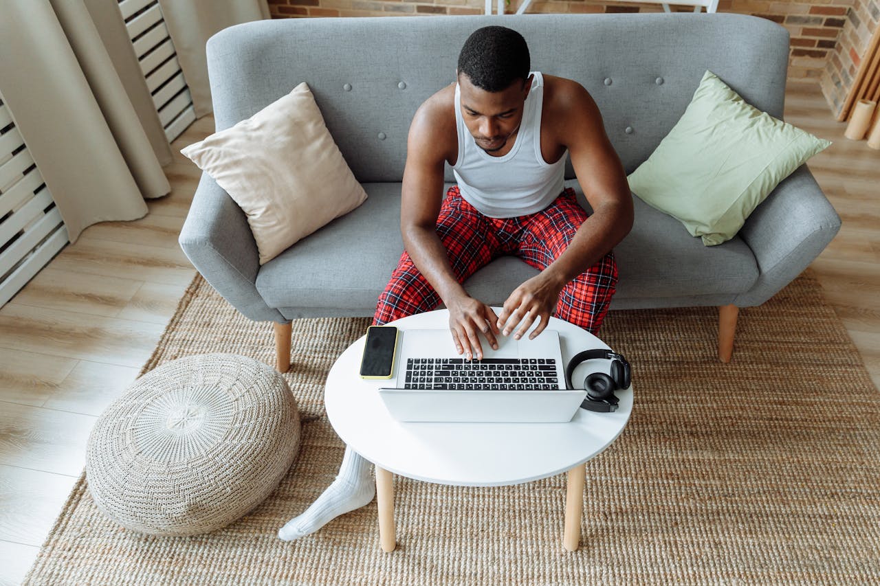 Casual adult man using laptop at home on a comfy sofa. High angle view in a modern living room.